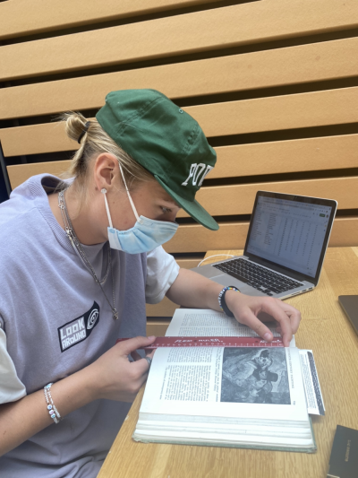 Holland working at a table in the Broadhead Center, measuring an entry with a ruler.